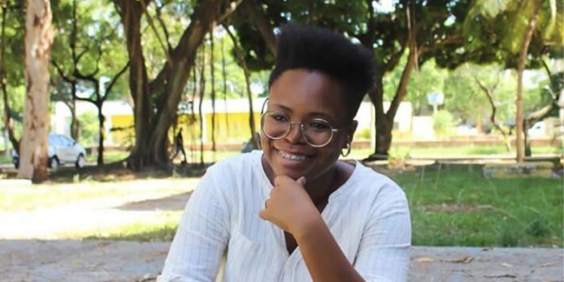 Mulher sentada em um gramado sorrindo