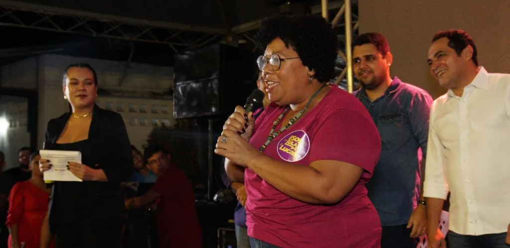 Na foto, mulher negra segura um microfone