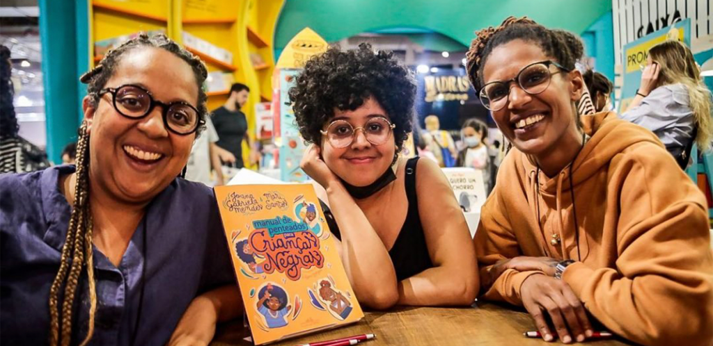 Foto mostra Joana, Flávia e Mari durante o lançamento do livro na Bienal