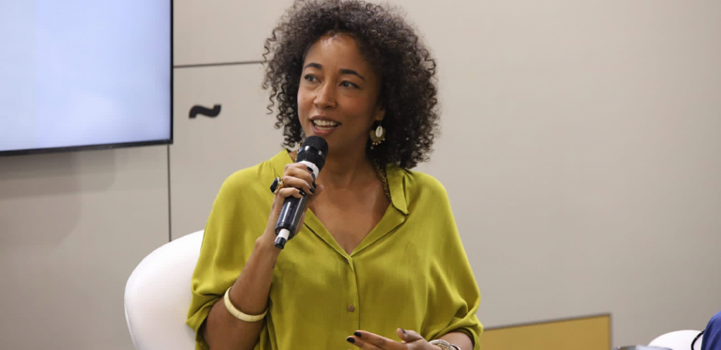 Foto mostra Patty Durães segurando microfone durante palestra