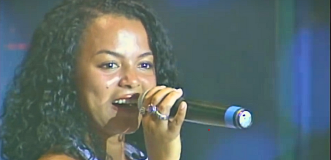 Foto mostra Mc Cacau segurando microfone durante apresentação