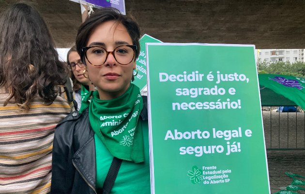 Foto mostra Giuliana segurando uma placa com o texto: 