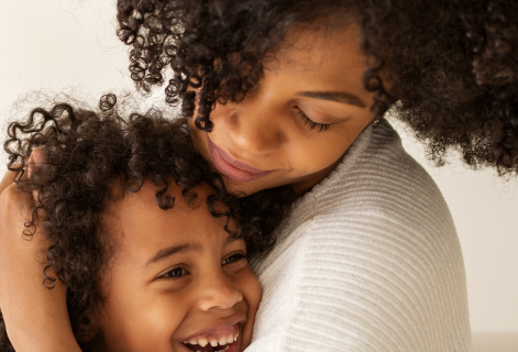 Foto mostra mãe abraçando criança