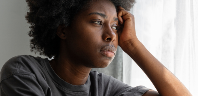 Foto mostra mulher triste olhando pela janela