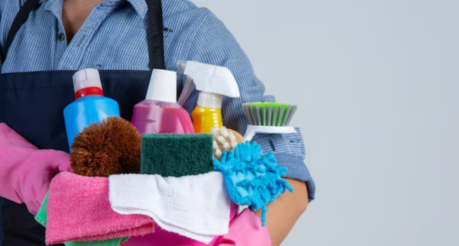 Foto mostra mulher, representando as diaristas, segurando materiais de limpeza