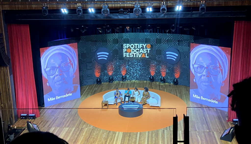 pessoas em palco, com imagem de Mãe Bernadete em dois telões