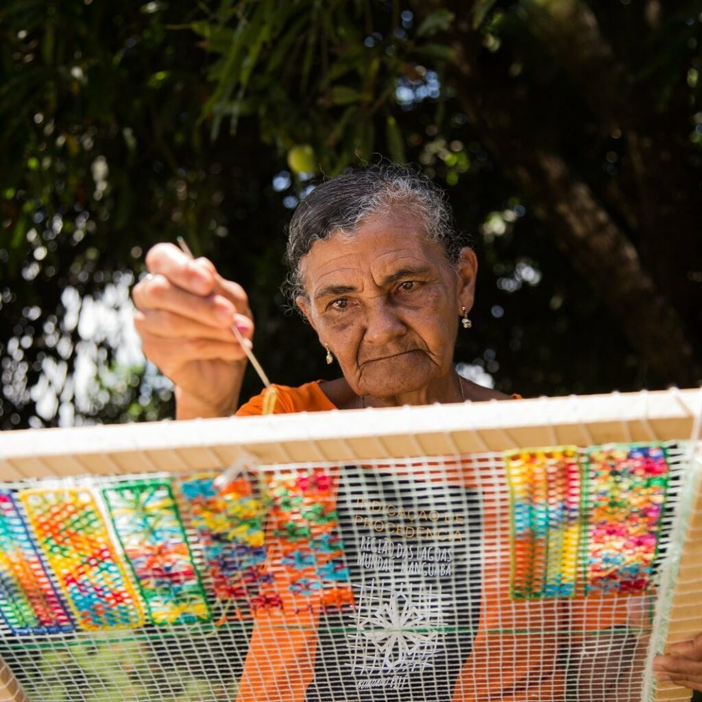 senhora bordando filé com as mãos em uma tela