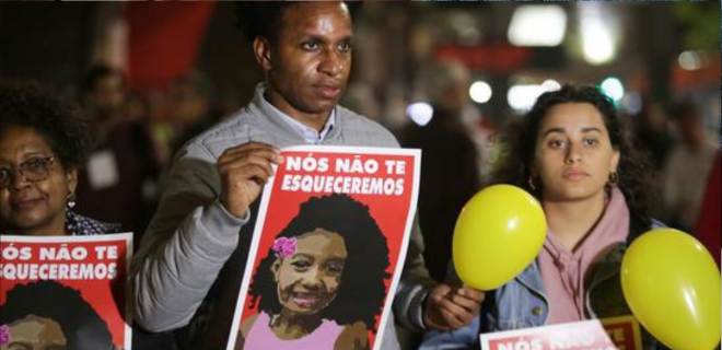 Foto mostra família de Ágatha segurando um cartaz com sua foto e o texto nós não te esqueceremos