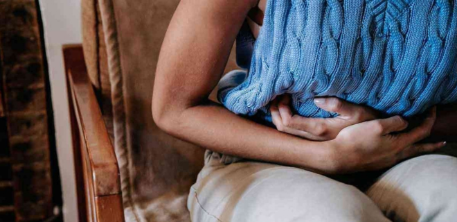 Foto mostra mulher com endometriose com as mãos na barriga