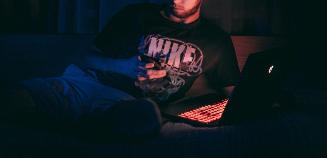 Foto mostra homem mexendo no celular e no computador, representando os incels