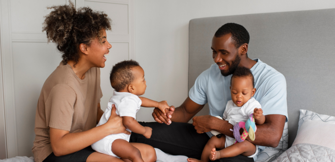 Foto mostra pai e mãe brincando com bebês