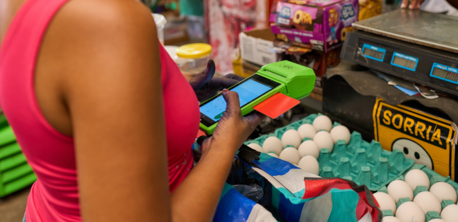 Foto mostra mulher pagando conta em mercadinho