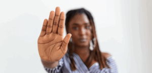 Foto mostra mulher com a mão em sinal de pare, contra a violência doméstica