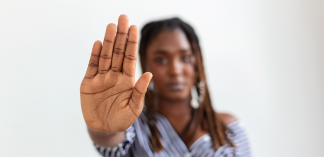 Foto mostra mulher com a mão em sinal de pare, contra a violência doméstica