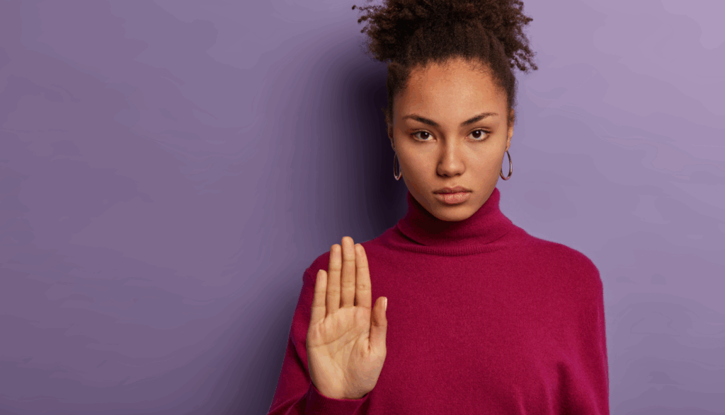 mulher séria mostra palma da mão como gesto de rejeição-