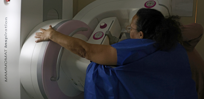 Foto mostra mulher fazendo o exame de mamografia