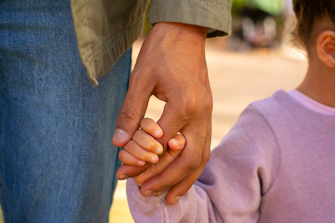 criança e adulto de mãos dadas