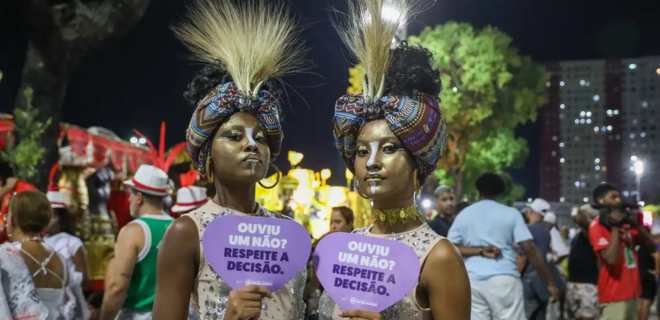 Foto mostra mulheres segurando placa de campanha contra o assédio no carnaval