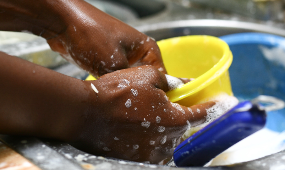 mão feminina negra lavando uma tigela amarela